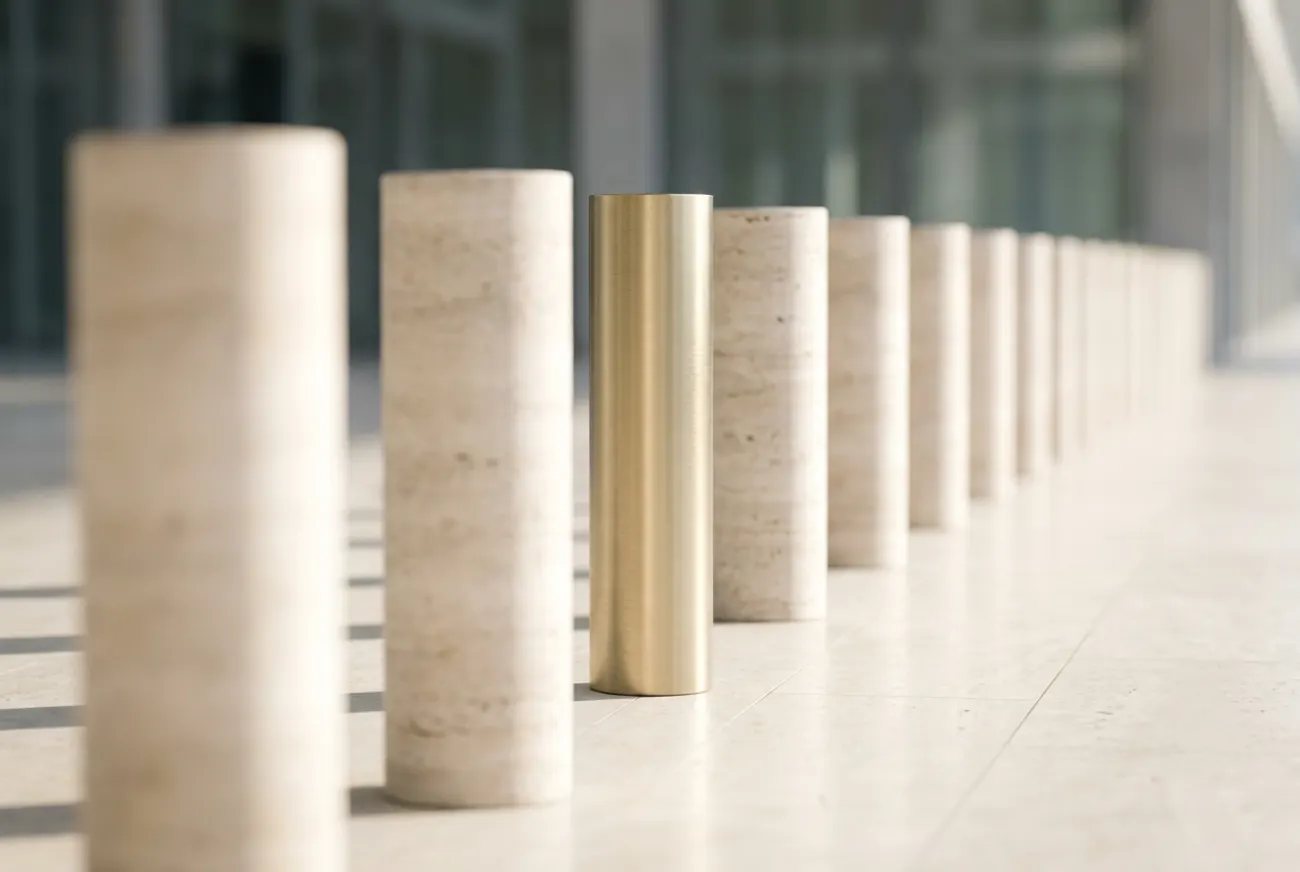 Identical stone bollards with one clad in brass